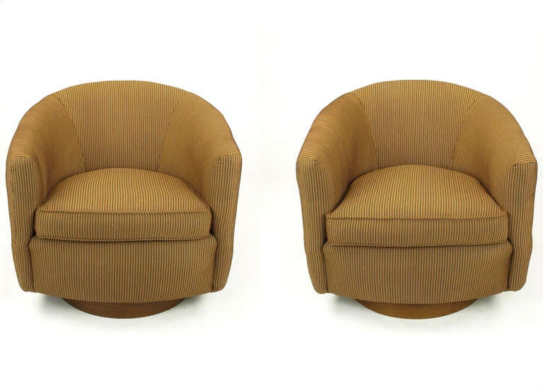 Pair of recently reupholstered swiveling barrel back lounge chairs with walnut veneered base.  Loose seat cushion and interesting welt surrounding back and sides. Newer thin stiped upholstery is in perfect condition. Milo Baughman  attribution. 
