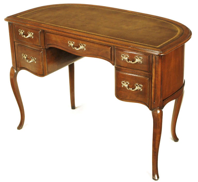 Elegant and timeless walnut and tooled brown leather top curved front five drawer desk or writing table from Sligh. Cabriole legs and scalloped bottom and centre drawers as well as curved apron. Heavy cast brass filigreed pulls.