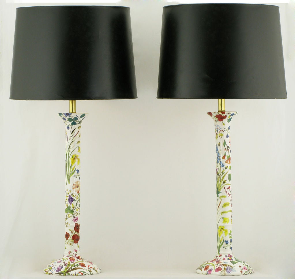 Pair of Italian ceramic columns, with flanged base and capital. White ceramic bodies are decorated with flowering foliage in greens, blues, reds, lavenders & yellows. Sold sans shades.