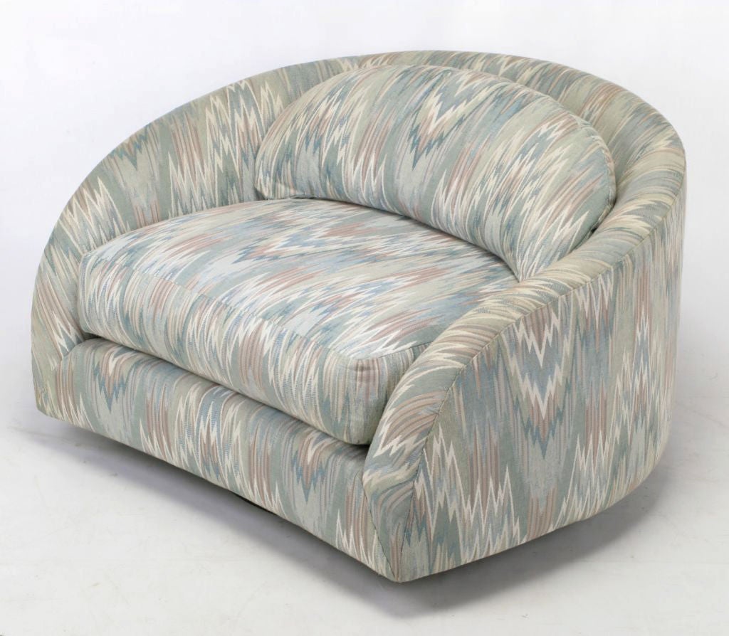Swiveling barrel back club chair in a periwinkle blue and rose flame stich upholstery. Low slung and extremely comfortable with wide, loose cushions. Possibly a custom design inspired by Milo Baughman's work for Thayer Coggin.  Matching chair with