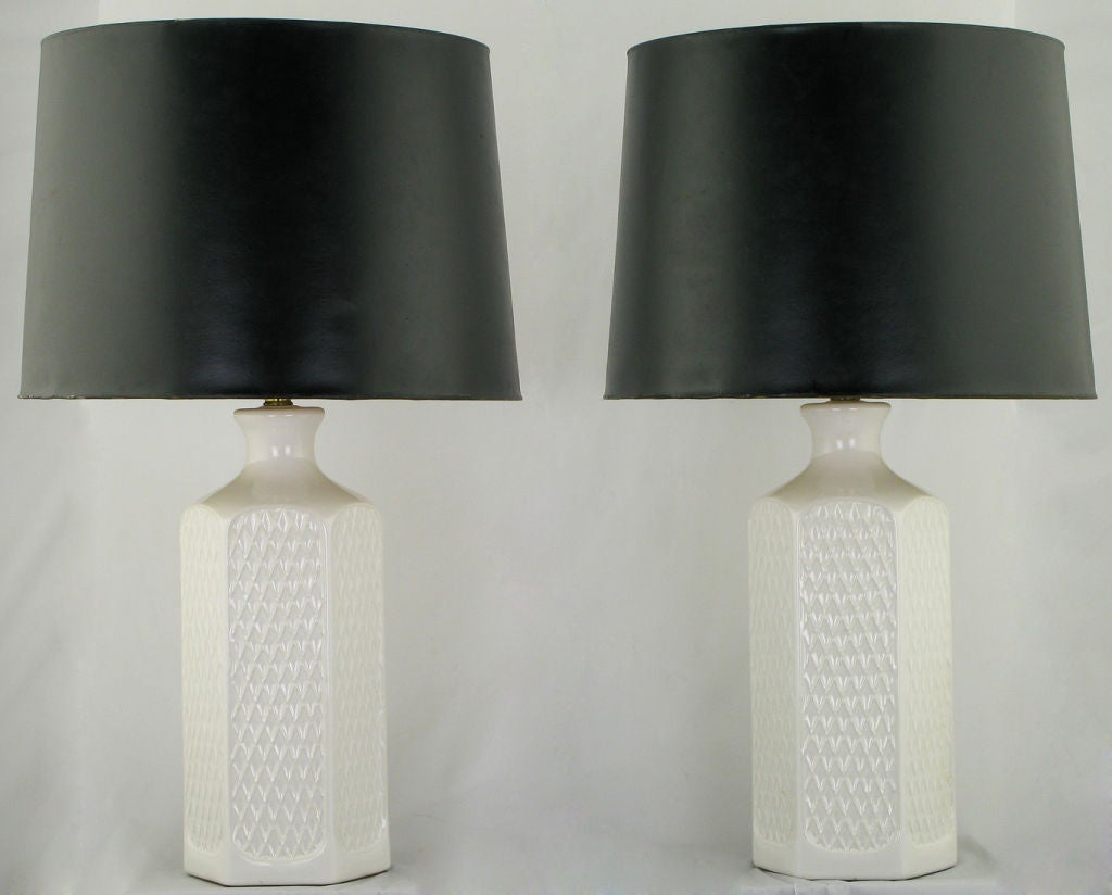 Pair of hexagonal white ceramic vessel table lamps with a raised relief of open triangles (or Vs) on every side. Sold sans shades.