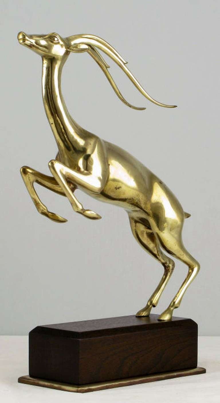 Expertly cast and finished brass leaping gazelle sculpture mounted on a brass plinth based walnut pedestal.