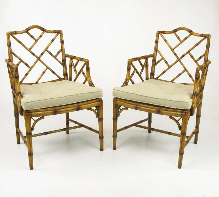Pair of restored Hekman Chinese Chippendale faux bamboo armchairs. Button tufted seat cushion in natural linen is capable of being fixed or loose; cane seat underneath. Traditional Chinese flamed finish is replicated with tinted lacquer and applied