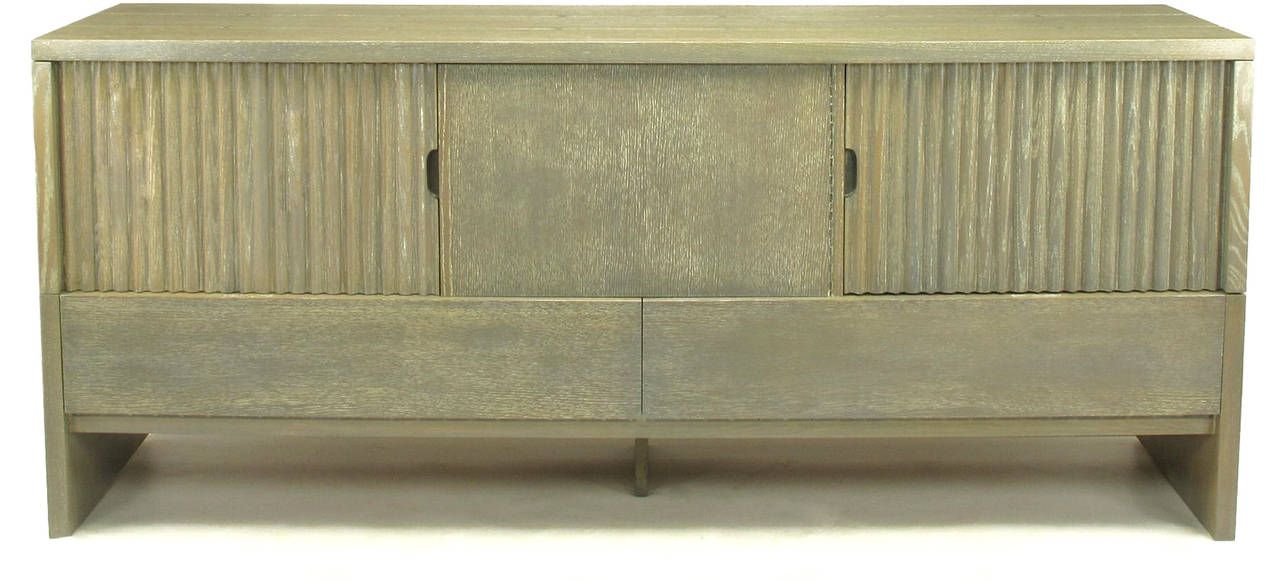 7 foot long cerused oak sideboard by Harold Schwartz for Romwber. Oak plank construction with bow tie joinery. Three front doors, two carved and fluted, open to reveal shelf space to the sides and three silverware drawers to the center. Long, drop