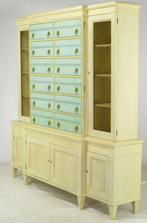Stunning ivory lacquered design by Renzo Rutili for Johnson Furniture. Robin's egg blue embossed leather fronts, with brass drop ring pulls, that appear to be all drawers. Starting from the bottom, the lowest pair of drawer fronts conceal a pull-out