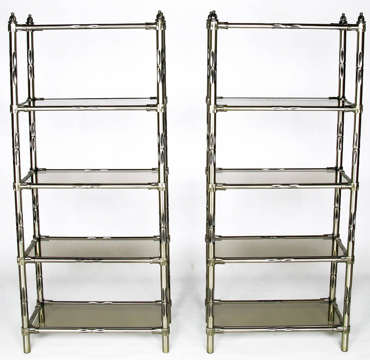 Pair of metal faux bamboo étagère in an antiqued nickel, or gunmetal, finish. They feature rugged cast metal joinery and smoked glass shelves, surmounted by cap and ball finals.