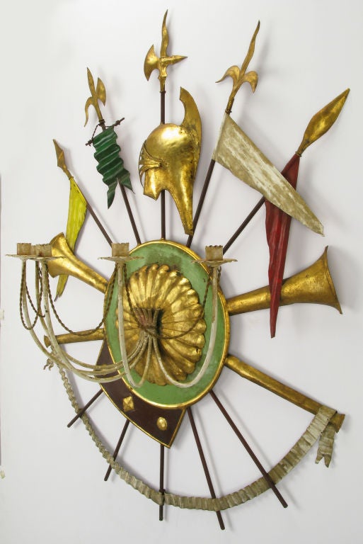 Renaissance revival tole metal wall hanging candelabra finished in gold leaf, silver leaf and green, red, yellow and brown lacquer. Center shield supports the five arm candelabra and serves as the center point for the crossed gilt trumpets and