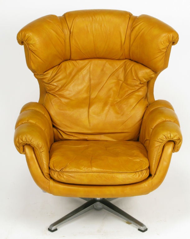 Overman of Sweden, swiveling pedestal lounge chair with matching ottoman. Pumpkin leather-like strapped, buckled and tufted cushions over a vinyl clad egg shaped chair. Leather-like strap-tufted ottoman measures 17