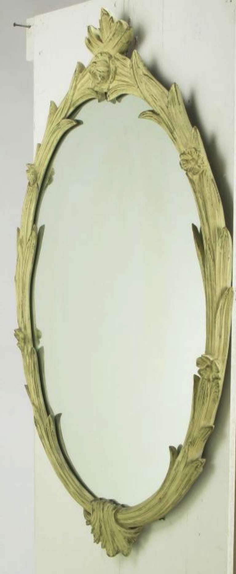 An exceptional mirror in hand-carved wood with foliate detail. Gold leafed, and then finished in a distressed ivory wash to reveal the gilt underlayer. Very fine carving and some aging to the mercury backing give this mirror character.