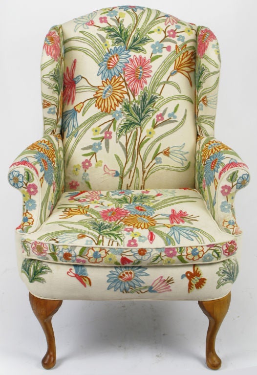 Classic wing chair with crewel upholstered front in blue, teal, umber, green and pink. The sides and back are upholstered in the same cream wool that backs the floral embroidered crewel loose seat cushion, arms, wings and back. The front cabriole