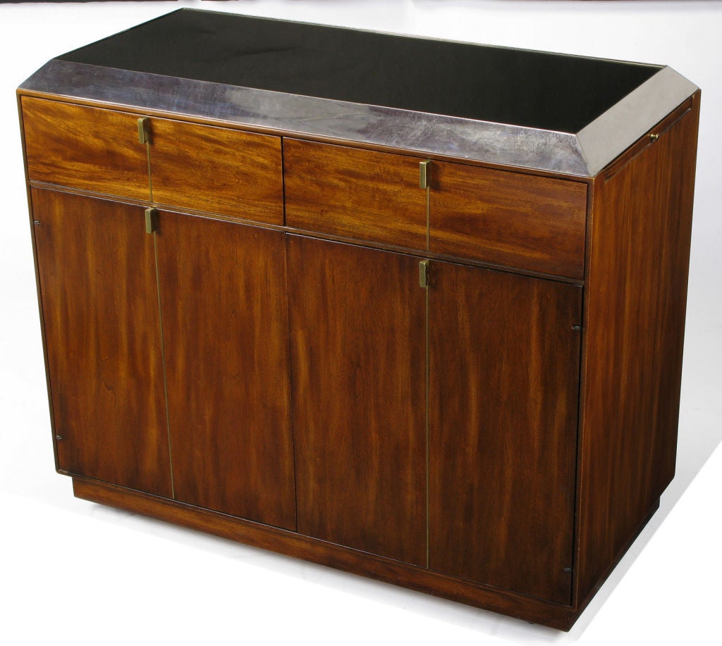 Early Hickory Furniture rolling bar cabinet or serving cabinet in figured walnut.  Solid brass minimalist pulls with straight line brass inlay that bisects each of the two drawers and pair of doors. Recessed beveled edge top has a black mirrored