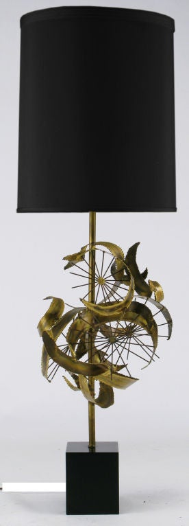 Large scale brutalist table lamp by Laurel Lamp Company. Body of the lamp is comprised of a brass stem with brass rod sunbursts and torch cut brass curved ribbon sculpture. The base is black lacquered metal cube. Sold sans shade.