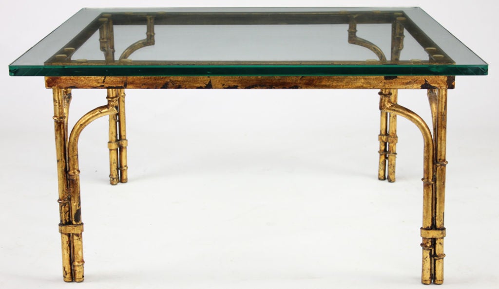 Bamboo-form metal coffee table finished in aged gold leaf with square glass top. Each leg is three part bound columns with the outer column finished in corner brackets.