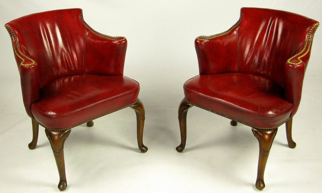 Upholstered in beautifully aged deep red claret leather, these armchairs were made by S.J. Campbell Co., a venerable furniture maker in Chicago history. Vertically rolled arms, cabriole legs, and brass nailhead trim complete the ensemble.<br />
<br