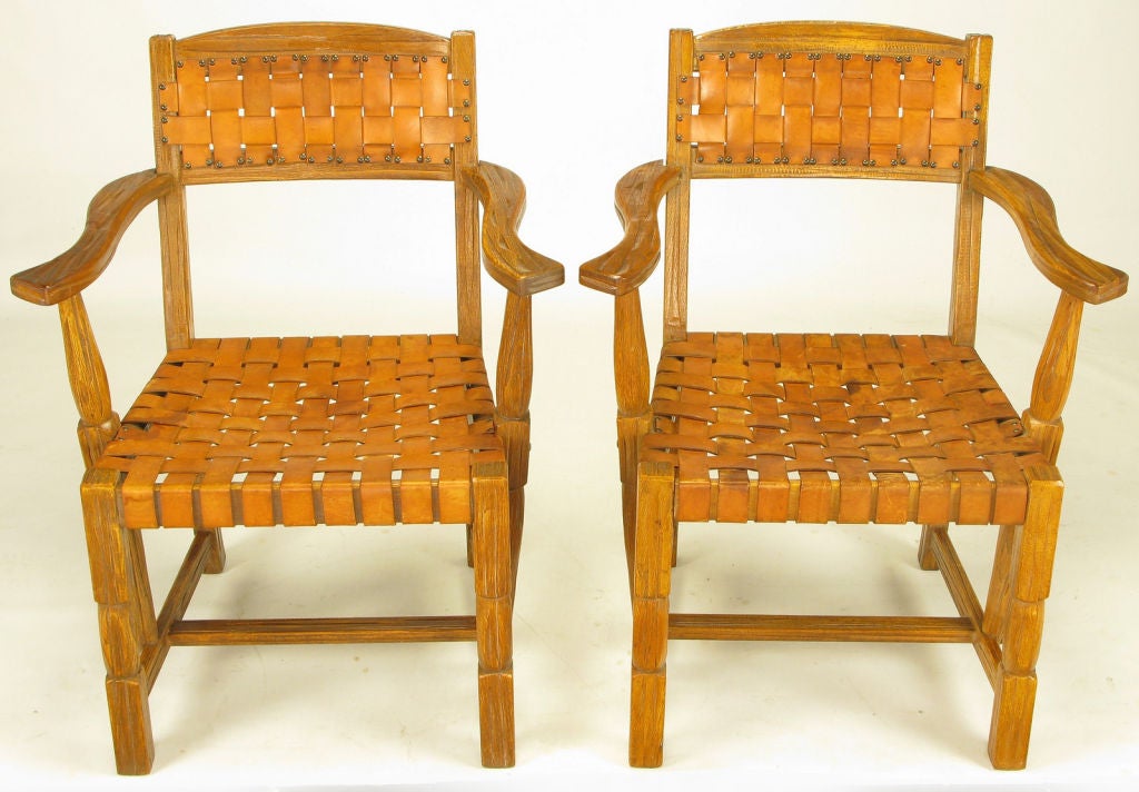 Pair of sculpted white oak arm chairs with woven umber leather strap seats and backs with brass nail head upholstery tacks.<br />
<br />
A. Brandt Ranch Oak Furniture was made for nearly fifty years in Fort Worth, Texas and has been