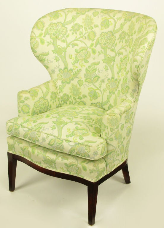 Uncommon wide wingback chair with a embroidered green, yellow and taupe linen upholstery. Simple clean line mahogany curved front apron and legs.  A documented and very early Wormley design by Dunbar.