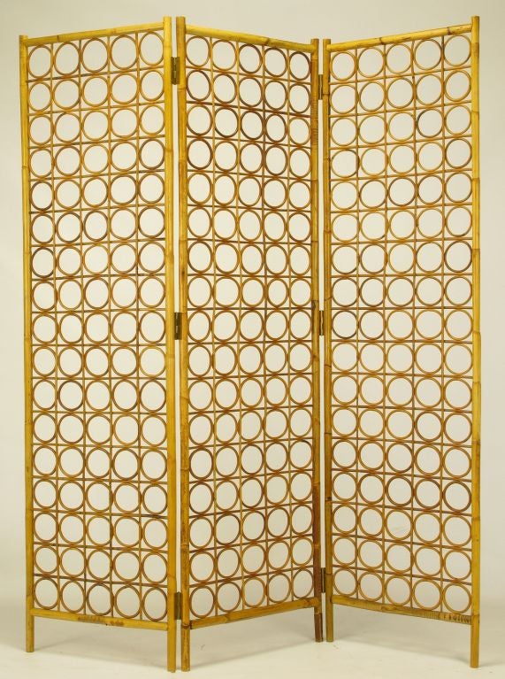 Architecturally intriguing three part bamboo and rattan screen or room divider. Bamboo frame is hinged at three places and the screens them selves are a combination of rattan crosses and O's.