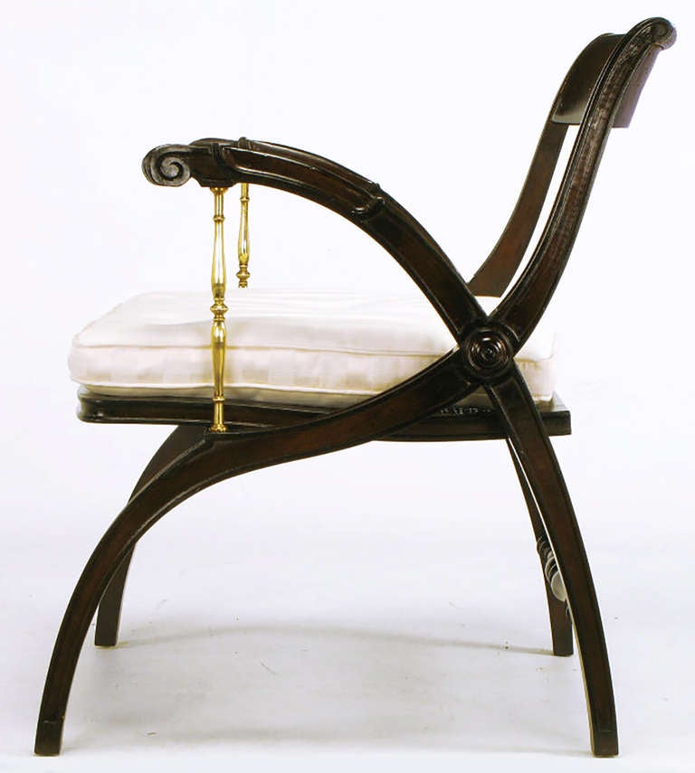 Poltrona con struttura a X in stile Regency con braccioli in ottone fuso, schienale aperto e curvo, cuscino rimovibile con bottoni di seta a righe e seduta con pannello a canne. Bracci e barella posteriore ben intagliati con una rosetta al centro