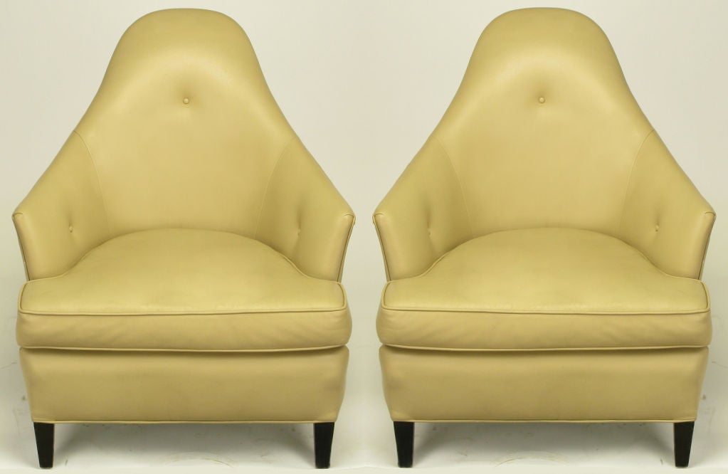 Pair of Ghost club chairs in taupe leather upholstery designed by John Hutton for Donghia. Early version with loose seat cushion, three button tufted, rounded back and arms. Chunky ebonized tapered wood legs. Original leather in very good restored