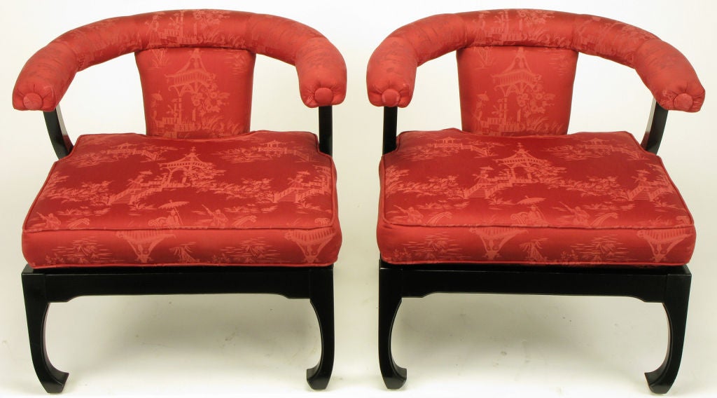 Pair of Chinoiserie lounge chairs with black lacquered Ming style legs and apron.  Red pagoda scene printed silk upholstered seat, back and curved arms. Uncommon, and likely custom, variation of the more common low yoke backed lounge chairs offered