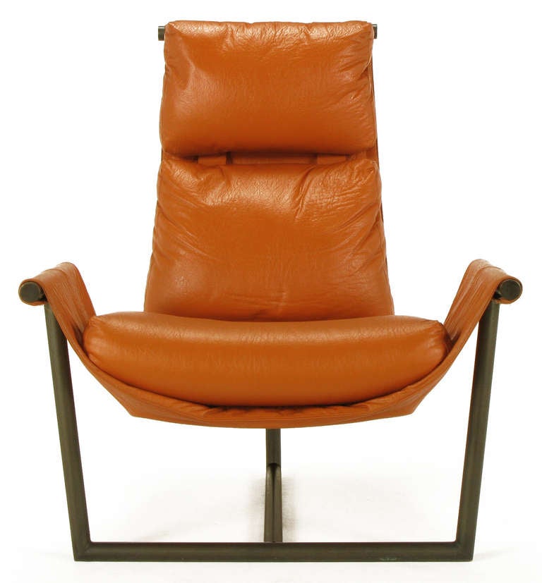 Architecturally inspired tubular steel T base, arms and back sling chair in pumpkin leather-like upholstery. Metropolitan Furniture was a forward thinking furniture company in South San Francisco founded by Heumann