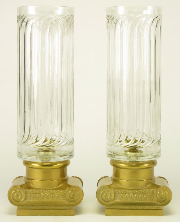 Pair of Greek revival hurricanes with brass Ionic capital style bases and fluted columnar glass shades.