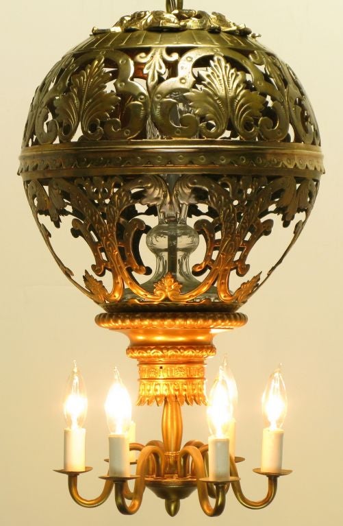 1930s converted gas to electric six arm chandelier. Top pierced brass globe, with a center glass pillar and the bottom lighting element, lends to the appearance of a hot air balloon. The illumination of a chandelier with the appearance of a pendant.
