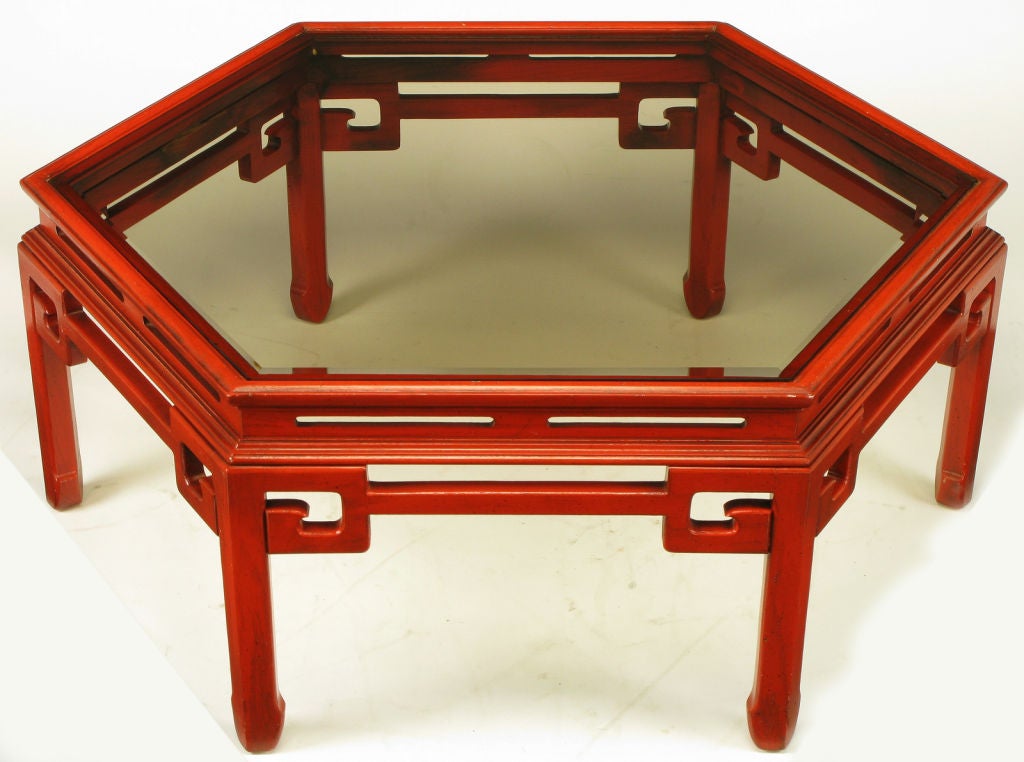Asian-design hexagonal glass top coffee table. Carved wood frame with six ming style legs, Greek key brackets and incised recessed apron. Finished in an aged cinnabar lacquer with black glaze.