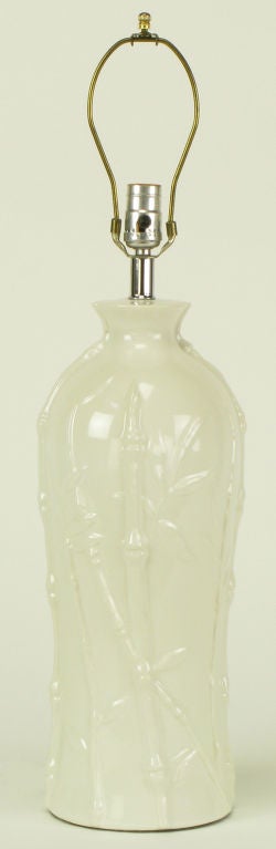 white glazed ceramic table lamp in bottle form with bamboo stalk and foliate relief. Sold sans shade.