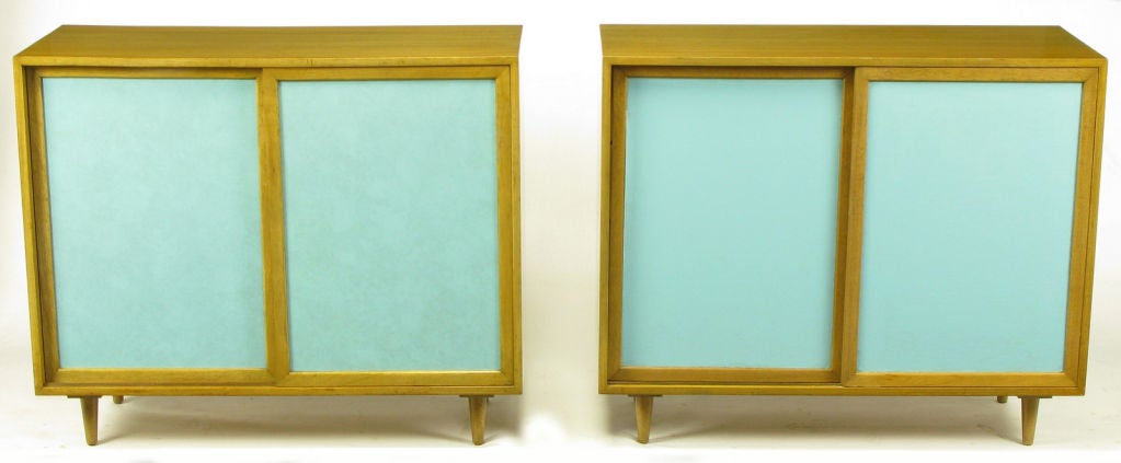 Rare pair of Harvey Probber two door cabinets with Tiffany blue leather inserts. Bleached and toned mahogany casement,conical legs, door frames and shelves. One cabinet features three  sliding shelves and two adjustable shelves, the other features