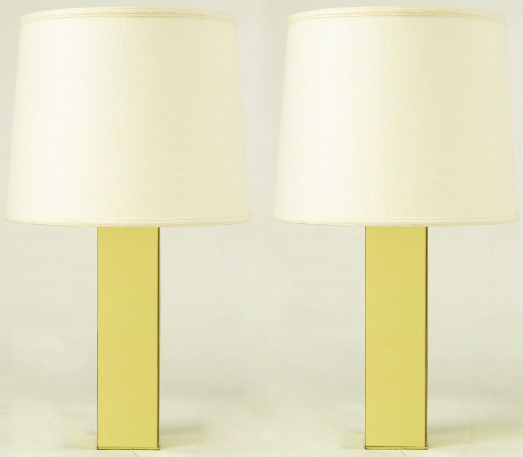 Pair of polished brass column bodied table lamps with brass stems and brass socket.