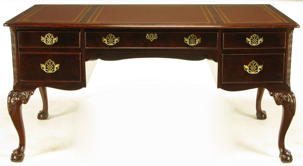 Sligh of Holland Michigan regency style desk in rich mahogany with figured drawer fronts and burled border around the three piece tooled red leather top. Cabriole legs with carved top detailing and ball and claw feet. Brass pierced escutcheons with