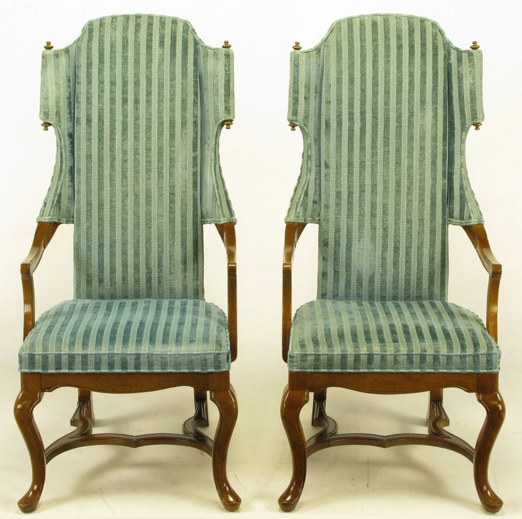 Tall back armchairs by Drexel with open sides and unexpected scrolled wings with top and bottom brass finials. Walnut frames with cabriole front legs, raked rear legs and undulating H-form stretcher. Upholstered in a silver blue cut silk velvet.