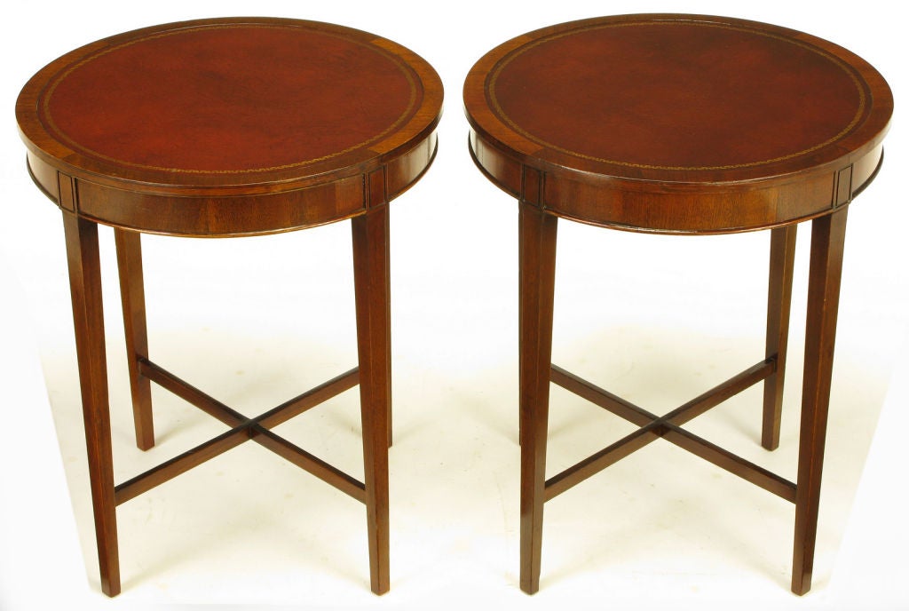 Pair of round mahogany end tables from quality table manufacturer Zangerle & Peterson (1892-1974) of Chicago. Round tooled leather tops with ribbon mahogany aprons. Long tapered legs with lower X stretchers.