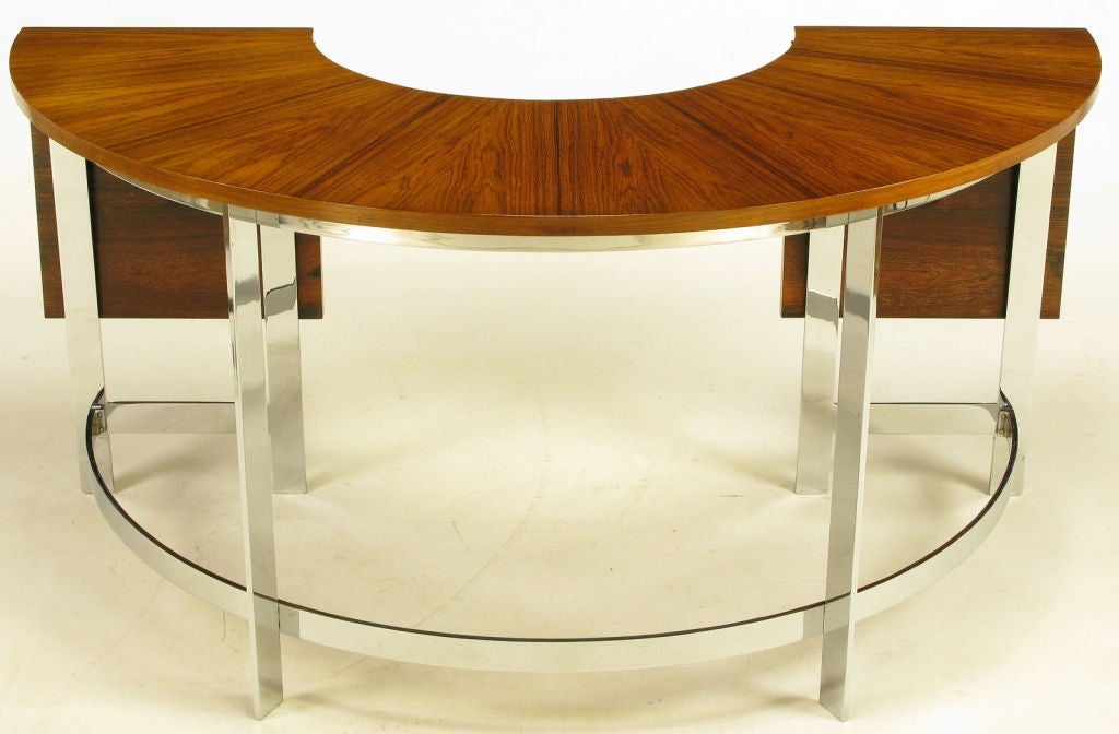 U shaped rosewood and open chromed steel base desk by famed Scandinavian furniture designer and architect, Hans Brattrud. Rosewood veneer over demilune shaped writing surface has two hinged panels that fold up when extra desk space is needed.<br