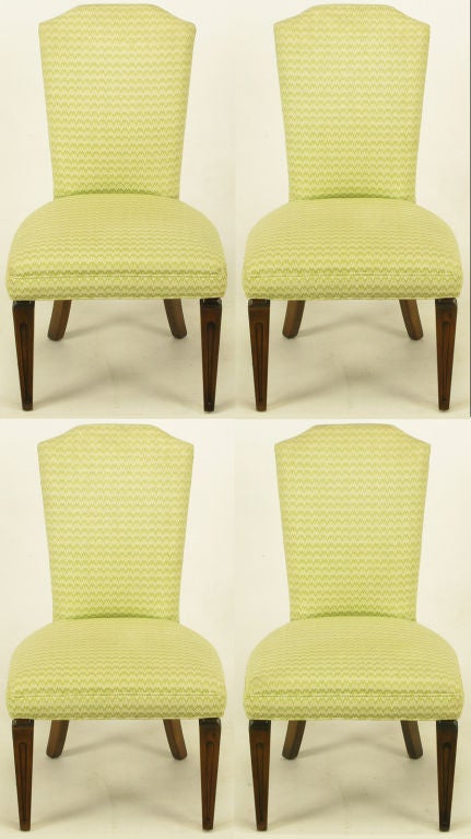 Set of four regency side chairs with carved and tapered walnut front legs and saber back legs. Upholstery is an apple green flame stitch blend. Perfect for a petite dining table or game table.