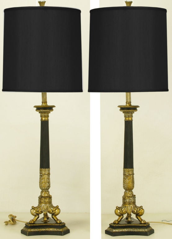 Empire revival table lamps with triple lions leg cast metal and gilt base and carved wood black lacquer and parcel gilt reverse trefoil beveled plinth. Black lacquer fluted columns.