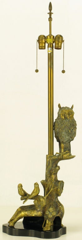 Marbro table lamp in cast brass on black lacquered resin base. The body is a brass sculpture of a forestal theme with a heavy tree branch and a single owl and two finches perched. Brass stem, socket cluster and ball and chain pulls. Sold sans shade.