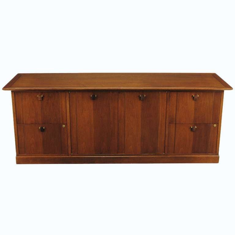 Edward Wormley for Dunbar mahogany cabinet with four large drawers and a center shelved cabinet on plinth base. The pair of cabinet doors and drawers are accessed by carved solid rosewood drop pulls that are mounted with solid brass squares and