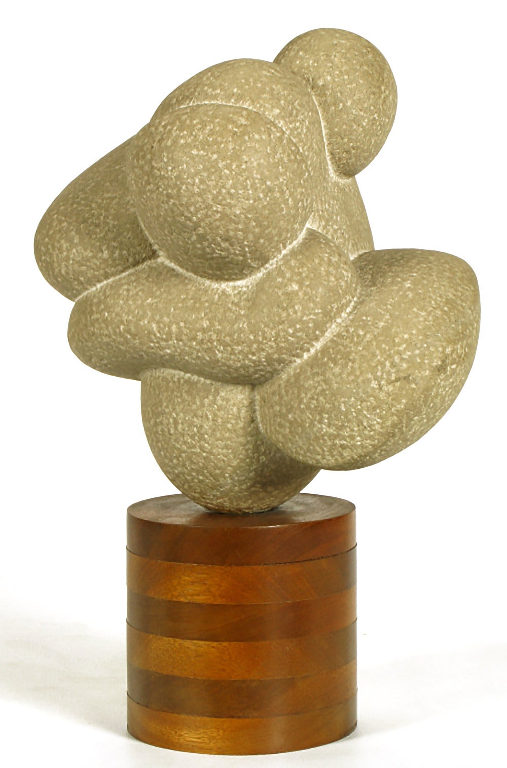 Carved stone sculpture mounted on a stacked wood cylinder base entitled 