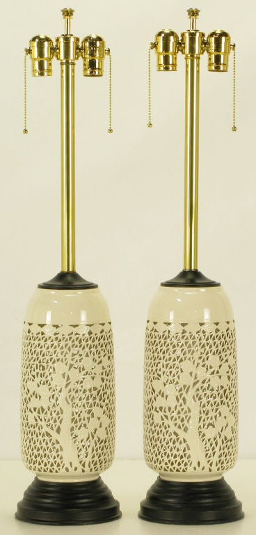 Pair of reticulated blanc de chine table lamps.  Single tree silhouettes to the front as well as the back. Black lacquered wood and metal base with black lacquered wood cap. Brass stem and dual socket cluster. Sold sans shades.