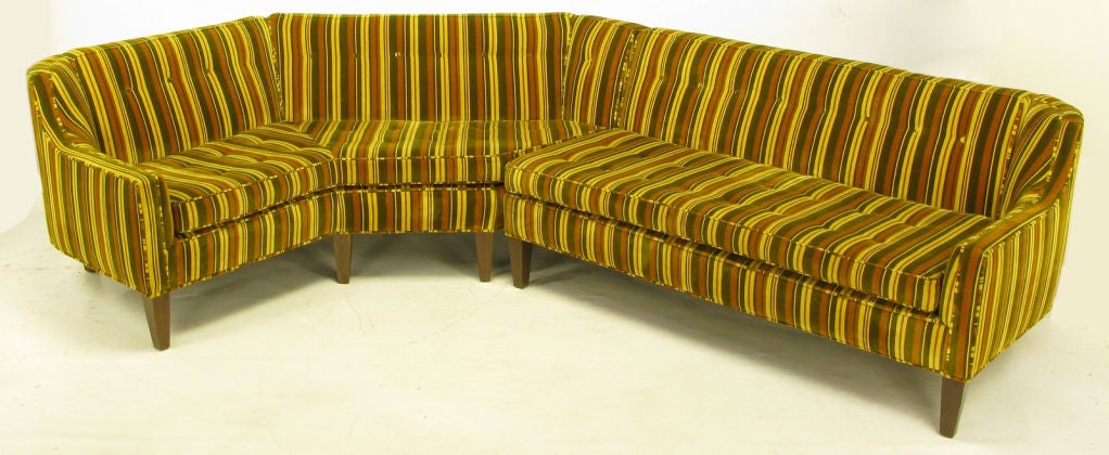 Classic 1950s two-piece sectional clad in button-tufted olive, gold, and umber striped velvet upholstery. Long tapered wood legs, curved corners and sloped arms with loose seat cushions. Possibly a Baker or Henredon manufactured piece.