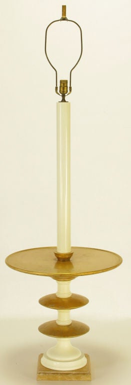 Gilt and ivory lacquered segmented pedestal base floor lamp. Gilded wood and ivory lacquered resin segments form the pedestal base with a round raised edge table top. Ivory lacquered resin column and single socket illumination. Sold with custom gold