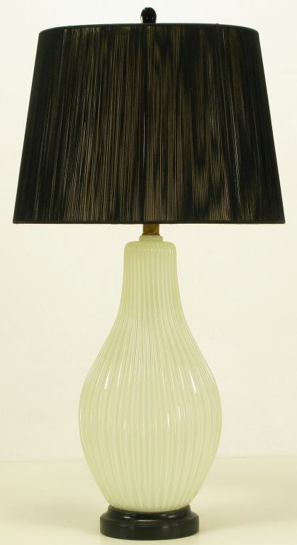 Ribbed and opaline Murano glass table lamp with black lacquered metal base. Elongated gourd form body with vertical ribbing. Brass stem and socket. Sold sans shade.