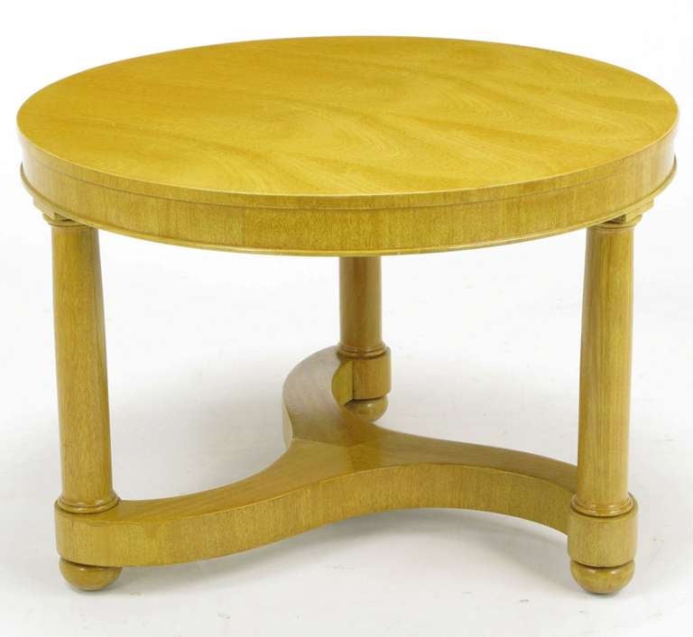 Empire style coffee or side table in bleached mahogany. Three pillar-like legs with square capitals and round feet are connected by a three arm pinwheel stretcher. Excellent design and build quality, on par with Edward Wormley's work for Dunbar.