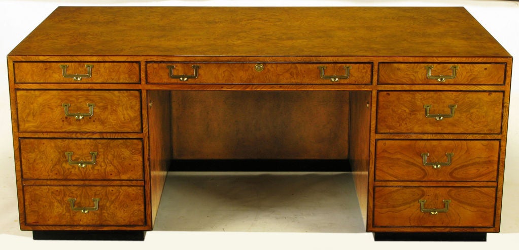 Beautiful burled walnut wood and black lacquered plinth base executive desk, from the Wellington Group, by the John Widdicomb Company. Brass recessed pulls, lower file-sized drawers, and front drawer with lock and key.