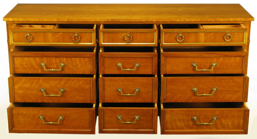 Bleached walnut nine drawer dresser from revered Grand Rapids, Michigan furniture maker, Kindel. Pictured framed and recessed drawer fronts with round escutcheons backing heavy cast brass drop U pulls. Top three drawers have brass framed panels with