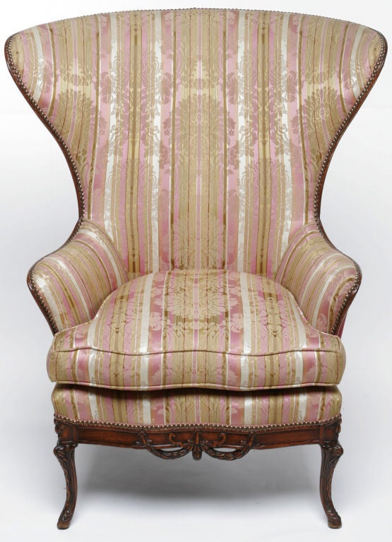 Early 20th century wingback chairs with delightfully exaggerated form, from Johnson Chair Company Chicago, IL. Carved wood legs and trim. Seating areas upholstered in a cream, gold and magenta damask. Backs upholstered in a rich magenta velvet.