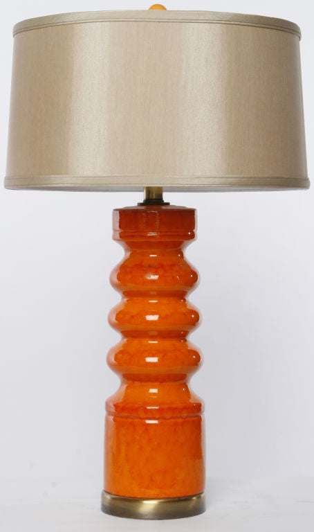 Pair of tangerine orange ceramic table lamps with a textured drip glaze finish. Antiqued brass bases and stems. Brass harp and socket. Sold sans shades.