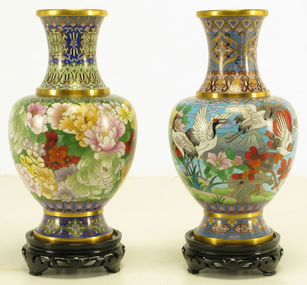 Pair of colorful Chinese cloisonne vases with green and blues being the primary colors. Both have floral background designs.  One vase features chrysanthemums and the other red headed herons. Made by Jingfa, award winning manufacturer of fine